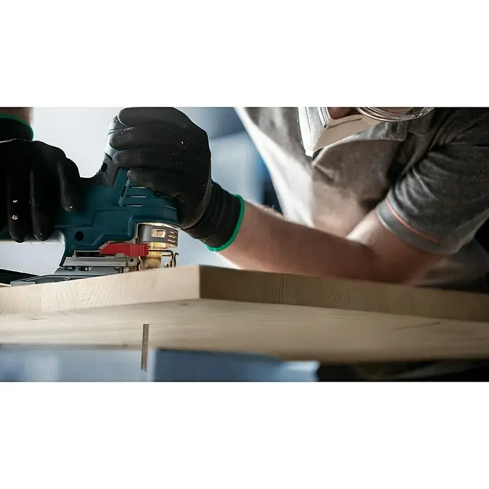 Bosch Stichsägeblätter Wood 2-Side Clean T308 BO - T-Schaft - Eine Person, die mit einer Stichsäge ein Stück Holz schneidet, wobei sie Handschuhe und eine Schutzbrille trägt, um Sicherheit und Präzision zu gewährleisten.