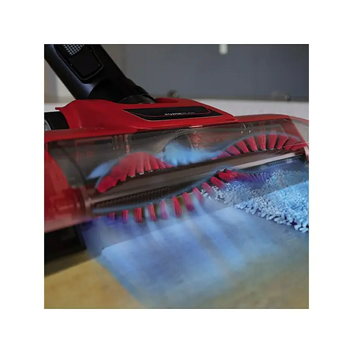 Einhell PXC 18V Aspirador de batería TE-SV 18 Li-Solo - 18 V, Sin batería, Volumen de recipiente: 0,6 l - Primer plano de una aspiradora con un cabezal de cepillo rojo que aspira partículas de suciedad, ilustrando la potencia de limpieza.