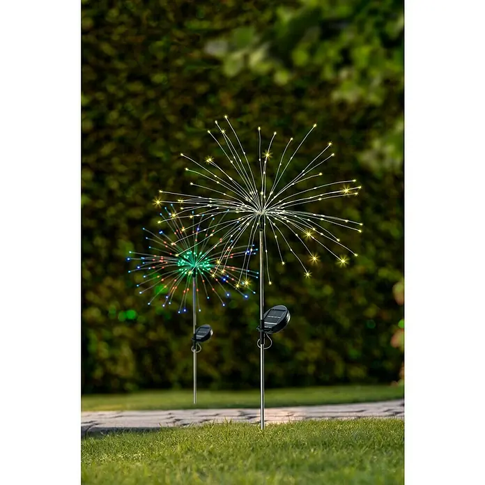 BAUHAUS Solarleuchte FeuerwerkHöhe: 90 cm, IP44, Lichtfarbe: Warmweiß - Zwei Solar-Feuerwerksleuchten im Garten. Eine leuchtet warmweiß, die andere in verschiedenen Farben. Die Lampen sind auf Metallstäben befestigt.