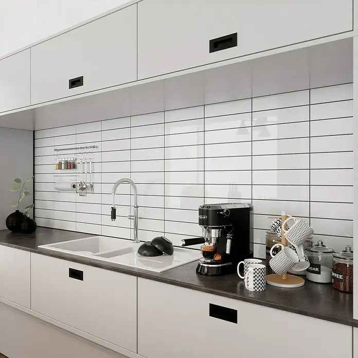 Modern Style Wandfliese Urban Blanco - 7,5 x 30 cm, Weiß, Glänzend - Eine moderne Küche mit weißen Schränken, einer schwarzen Espressomaschine und Zubehör auf der Arbeitsplatte.