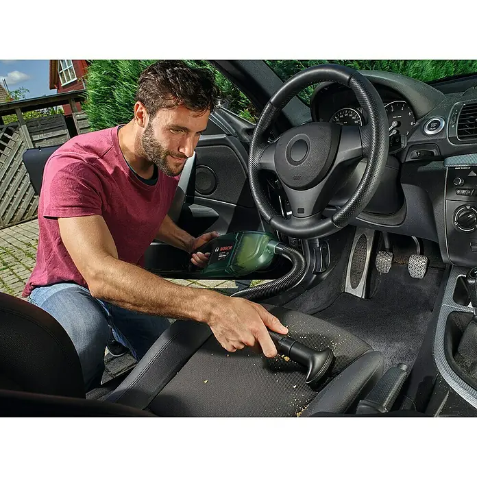 Bosch Power for All 12V Akku-Handstaubsauger EasyVac 12 - 12 V, Ohne Akku - Ein Mann reinigt mit einem Bosch-Akkusauger den Innenraum seines Autos, um Krümel zu entfernen.