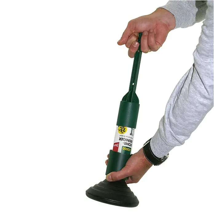 Steuber Rohrreiniger-Set - 125 ml - Eine Nahaufnahme einer Person, die einen grünen Rohrreiniger der Marke Glistin hält. Das Produkt ist in einer Kunststoffhülle verpackt.