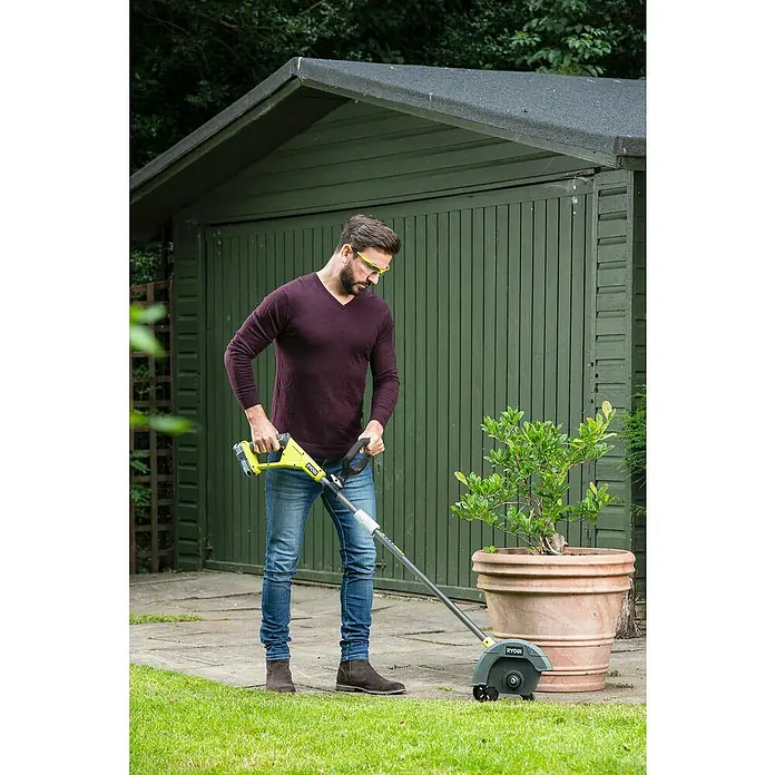 Ryobi ONE+ Cortabordes de batería RY18EGA-0 - 18 V, Iones de litio, Sin batería - Hombre usando un bordeador de césped Ryobi frente a un cobertizo de jardín.