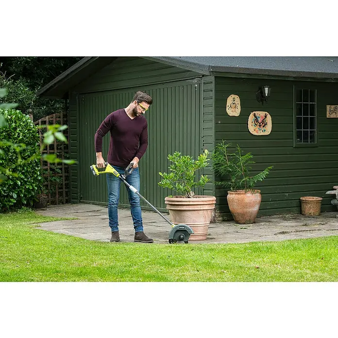 Ryobi ONE+ Cortabordes de batería RY18EGA-0 - 18 V, Iones de litio, Sin batería - Un hombre usa un bordeador de césped amarillo Ryobi para recortar los bordes del césped alrededor de una maceta.