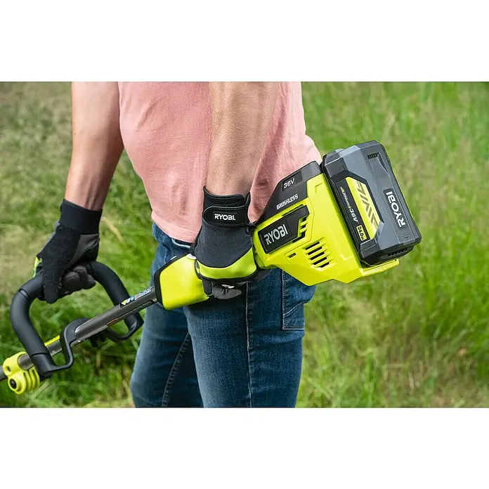 Ryobi Max Power Akku-Rasentrimmer RY36ELTX33A-0 - 36 V, Li-Ionen, Ohne Akku - Nahaufnahme eines Akku-Rasentrimmers Ryobi 36V, der von einer Person mit Handschuhen vor einem Rasenhintergrund gehalten wird.