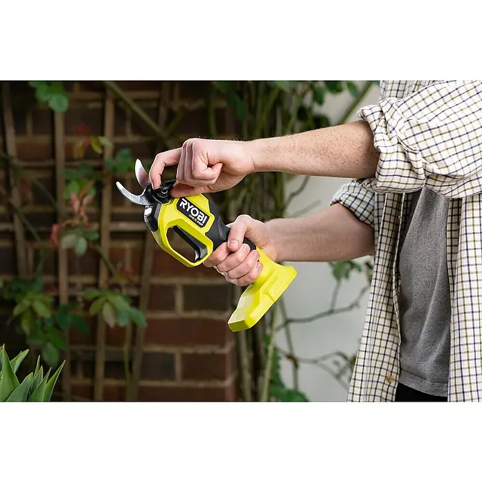 Ryobi ONE+ Maschinenpaket - Akku-Gartenschere RY18SCXA-0,18V, 4 Ah Akku & 2A Ladegerät - Nahaufnahme einer Person, die die Ryobi ONE+ Akku-Gartenschere benutzt, um einen kleinen Ast an einer Kletterpflanze im Garten zu schneiden.