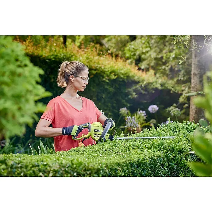 Ryobi Elektro-Heckenschere RHT4550 - 450 W, Schnittlänge: 50 cm, Max. Aststärke: 20 mm - Frau benutzt eine Ryobi Heckenschere, um eine Hecke zu schneiden.