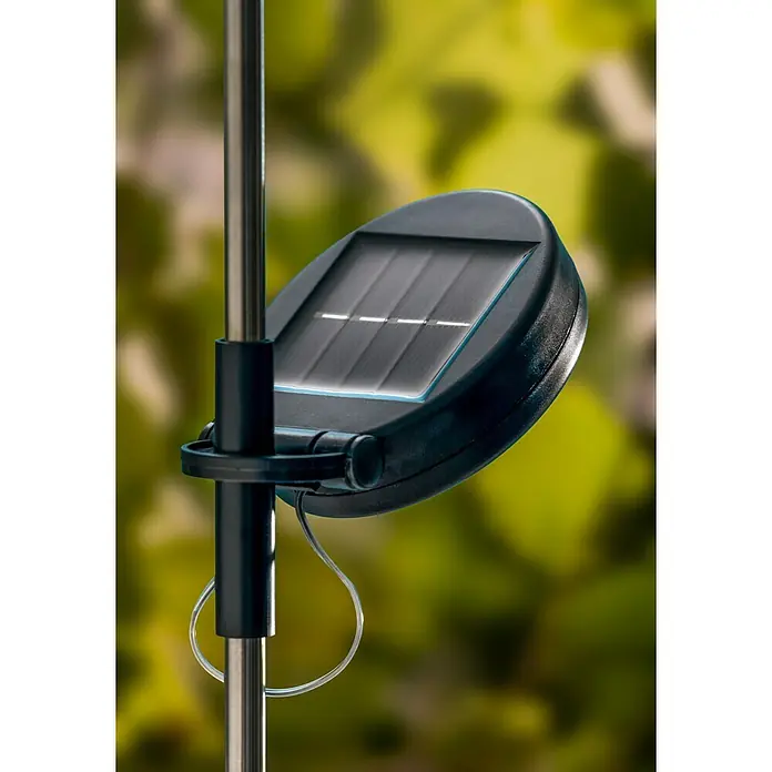 BAUHAUS Solarleuchte FeuerwerkHöhe: 90 cm, IP44, Lichtfarbe: Warmweiß - Nahaufnahme einer Solarleuchte mit Solarpanel, die an einer Stange befestigt ist, vor einem verschwommenen, grünem Hintergrund.
