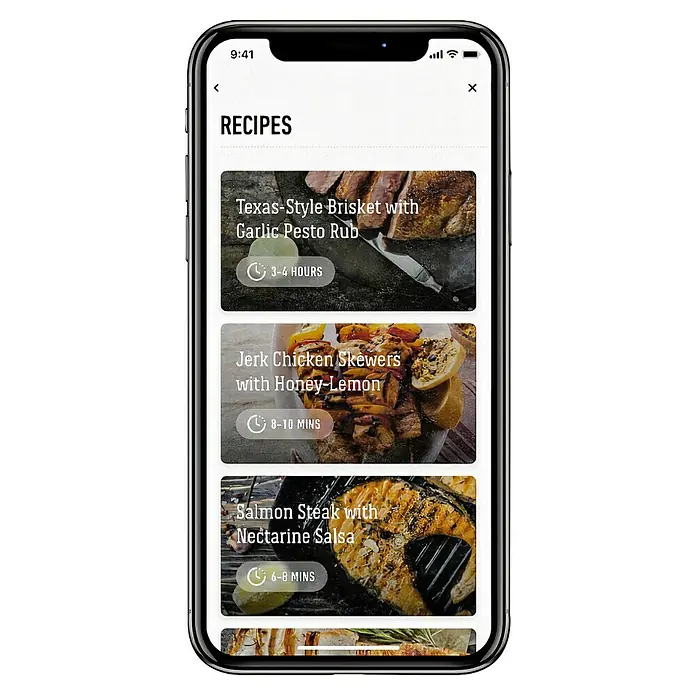 Weber Smart-Grill-Assistent - L x B x H: 9,8 x 3,4 x 7,5 cm - Ein Smartphone zeigt eine Rezepte-App mit köstlichen Gerichten wie Brisket, Hähnchenspieße und Lachssteak.