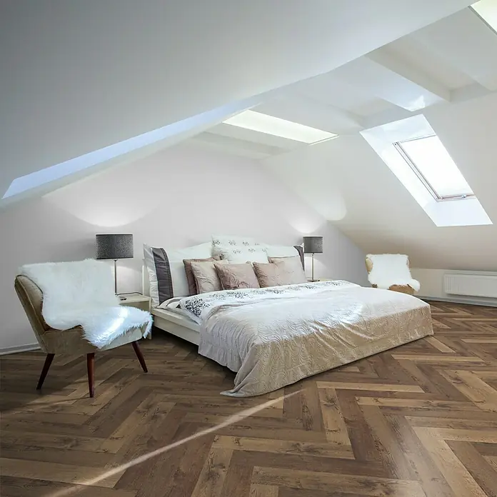 Vinylboden Isocore Inside - Alsace, Fischgrät, 720 x 120 x 8 mm - Geräumiges Schlafzimmer im Dachgeschoss mit einem stilvollen Bett, Nachttischen und zwei Sesseln, die den Raum komfortabel ergänzen.