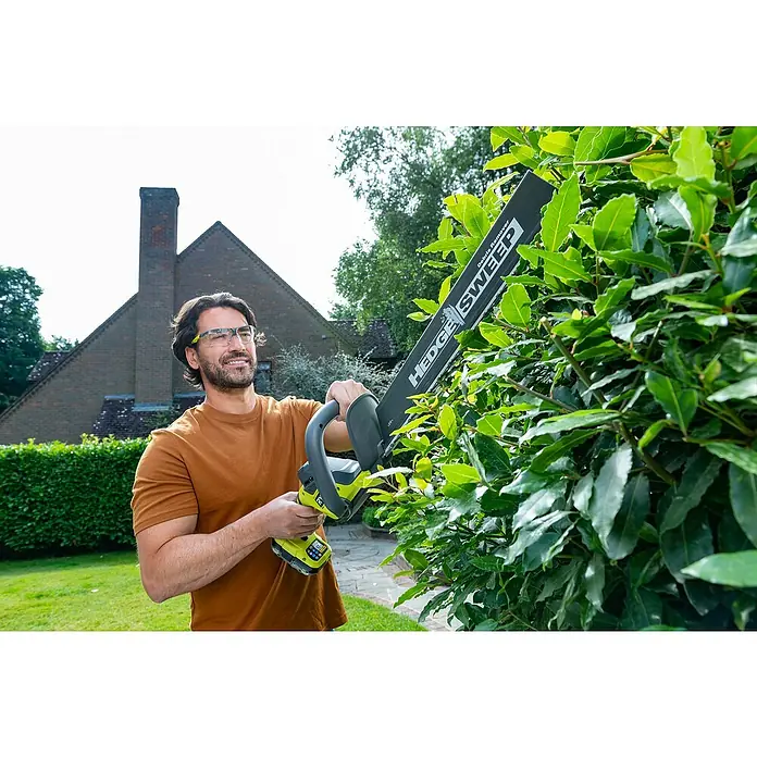 Ryobi ONE+ Akku-Heckenschere RY18HT45A-0 - 18 V, Li-Ionen, Ohne Akku - Ein Mann bedient eine Ryobi Heckenschere mit HEDGE SWEEP, um eine grüne Hecke zu schneiden, während er Sicherheitsbrille trägt.