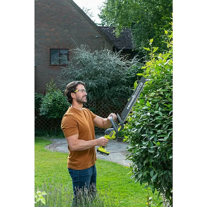 Ryobi ONE+ Akku-Heckenschere RY18HT45A-0 - 18 V, Li-Ionen, Ohne Akku - Ein Mann benutzt eine Ryobi Heckenschere, um im Garten eine Hecke zu schneiden. Praktisches und leistungsstarkes Gartengerät für präzise Ergebnisse.