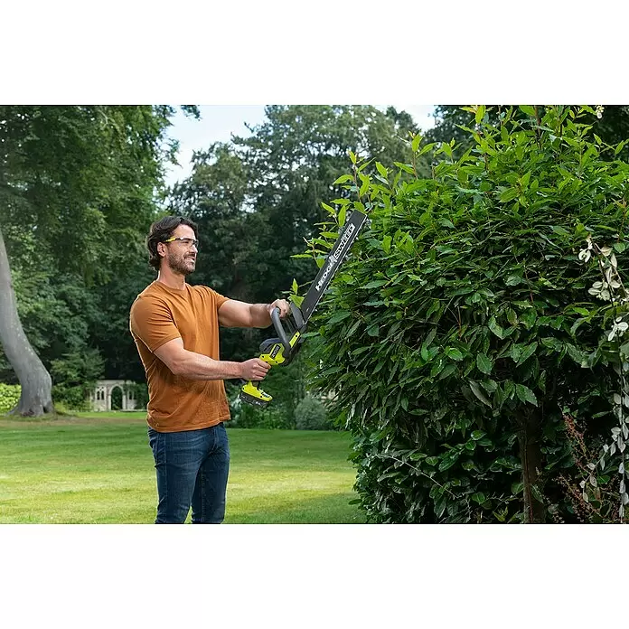 Ryobi ONE+ Akku-Heckenschere RY18HT45A-0 - 18 V, Li-Ionen, Ohne Akku - Mann mit Schutzbrille trimmt eine grüne Hecke mit einer grün-schwarzen Akku-Heckenschere.