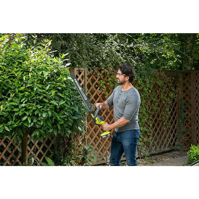 Ryobi ONE+ Akku-Heckenschere RY18HT50A-125 - 18 V, Li-Ionen, 1 Akku - Ein Mann im Garten benutzt eine Ryobi Heckenschere, um eine Hecke zu schneiden. Ryobi Heckenschere ist gut sichtbar.