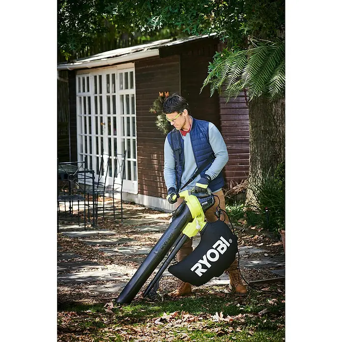 Ryobi Elektro-Laubsauger RBV3000CESV - 3.000 W, Blasgeschwindigkeit: 375 km/h, Blasleistung: 14 m³/min - Ein Mann benutzt einen RYOBI Laubsauger im Garten, um Laub zu entfernen. Praktisches Gartengerät für die Herbstsaison.