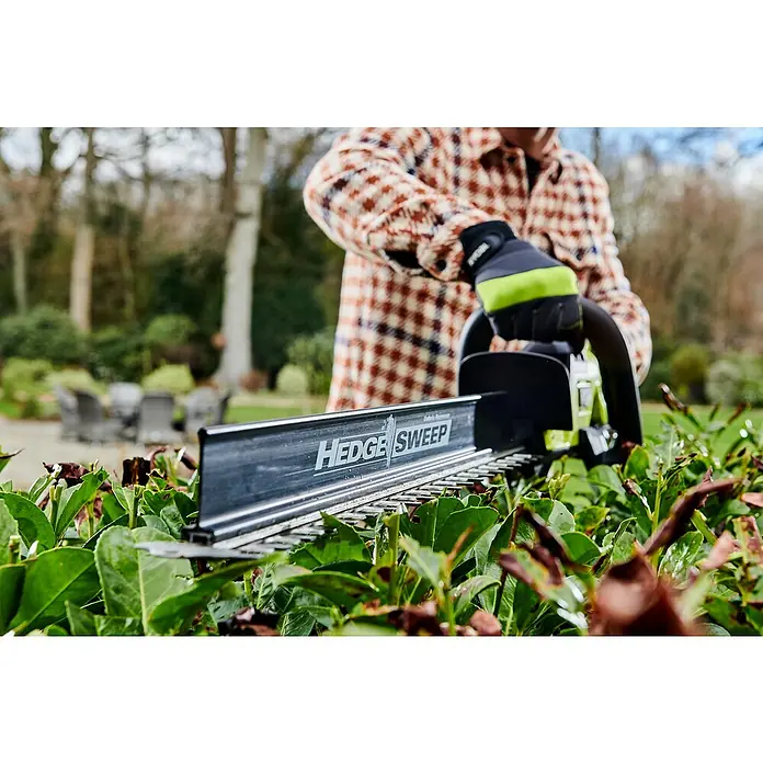 Ryobi Max Power Akku-Heckenschere RY36HTX65A-0 - 36 V, Li-Ionen, Ohne Akku - Eine Person, die mit einer "Hedge Sweep" Heckenschere einen Formschnitt an einer grünen Hecke vornimmt.