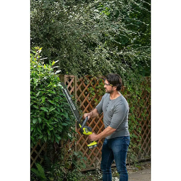 Ryobi ONE+ Akku-Heckenschere RY18HT50A-0 - 18 V, Li-Ionen, Ohne Akku - Ein Mann trimmt eine Hecke mit einer Ryobi Heckenschere, wobei der Fokus auf der Präzision des Werkzeugs und seiner Benutzerfreundlichkeit liegt.