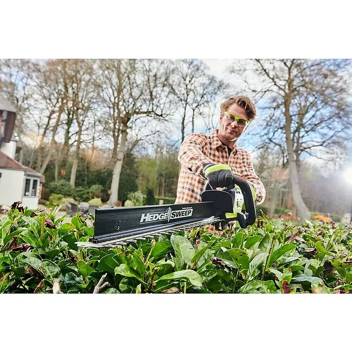 Ryobi Max Power Akku-Heckenschere RY36HTX65A-0 - 36 V, Li-Ionen, Ohne Akku - Ein Mann bedient eine Heckenschere der Marke "Hedge Sweep", um eine Hecke zu schneiden. Er trägt Schutzbrille und Gartenhandschuhe.