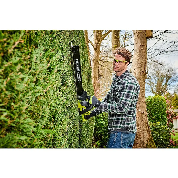 Ryobi Max Power Akku-Heckenschere RY36HTX65A-0 - 36 V, Li-Ionen, Ohne Akku - Ein Mann schneidet eine Hecke mit einer RYOBI Heckenschere mit Hedge Sweep Aufsatz, und trägt dabei Sicherheitsbrille und Handschuhe.