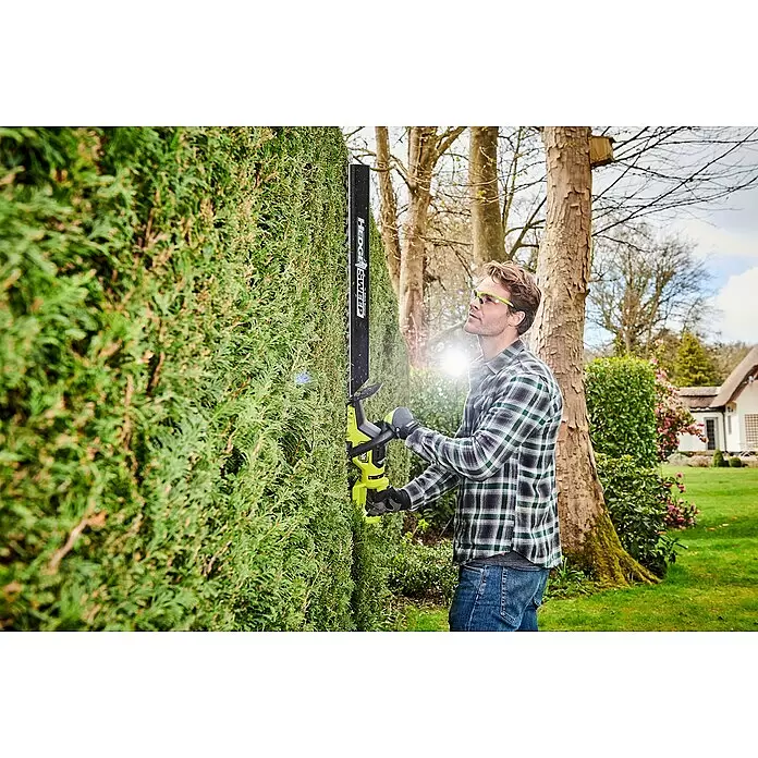 Ryobi Max Power Akku-Heckenschere RY36HTX65A-0 - 36 V, Li-Ionen, Ohne Akku - Mann schneidet mit schwarzem und limettengrünem Heckenschneider mit "HEDGE SWEEP" Aufsatz eine hohe grüne Hecke.