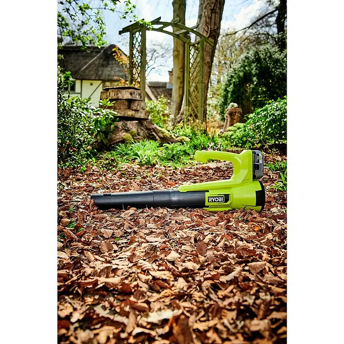 Ryobi ONE+ Akku-Laubbläser RY18BLA-0 - 18 V, Ohne Akku, Blasgeschwindigkeit: 145 km/h, Blasleistung: 7,1 m³/min - Laubbläser von Ryobi auf einem Beet mit Laub.