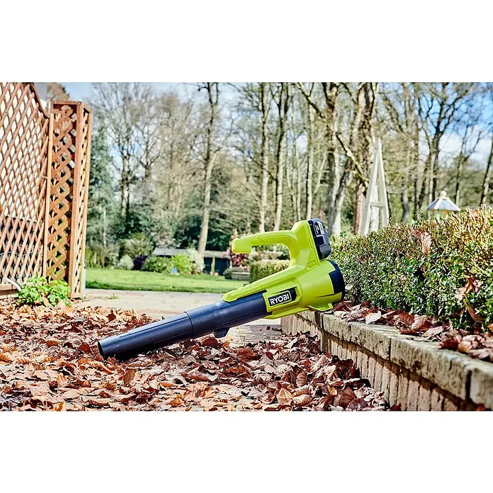 Ryobi ONE+ Soplador de hojas de batería RY18BLA - 18 V, Sin batería, Velocidad de soplado: 145 km/h, Potencia de soplado: 7,1 m³/min - Un soplador de hojas amarillo de Ryobi descansa en un patio lleno de hojas, listo para el trabajo de jardinería.