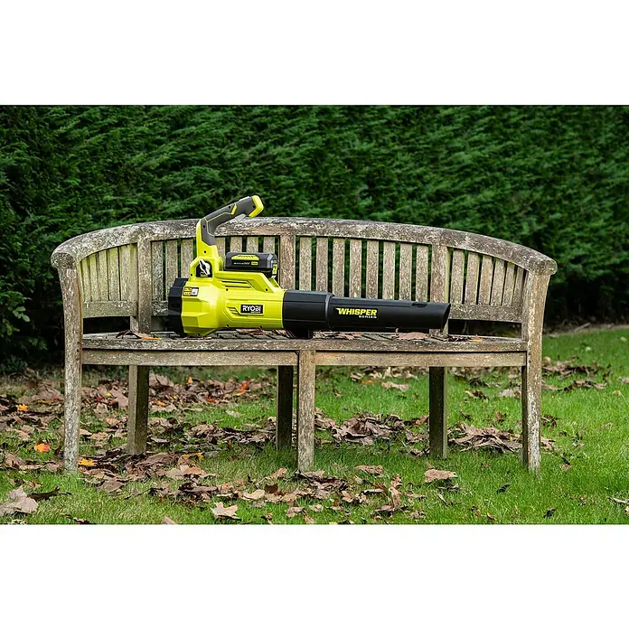 Ryobi Max Power Akku-Laubbläser RY36BLXA-0 - 36 V, Ohne Akku, Blasgeschwindigkeit: 176 km/h, Blasleistung: 15,6 m³/min - Der RYOBI Akku-Laubbläser "Whisper Series" liegt auf einer hölzernen Gartenbank vor einem grünen Busch. Ideal für die Gartenarbeit.
