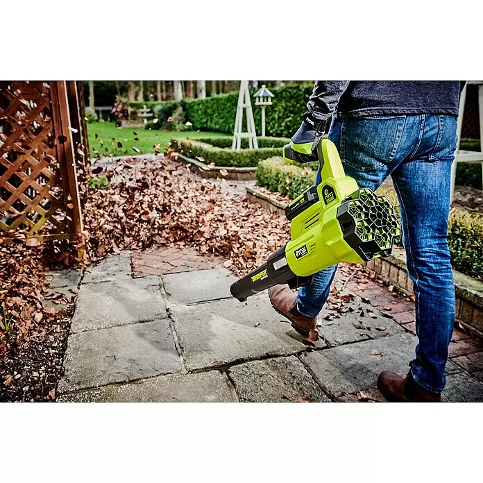 Ryobi Max Power Akku-Laubbläser RY36BLXA-0 - 36 V, Ohne Akku, Blasgeschwindigkeit: 176 km/h, Blasleistung: 15,6 m³/min - Person nutzt leuchtend grünen und schwarzen Laubbläser, um Herbstlaub vom Gartenweg zu entfernen.