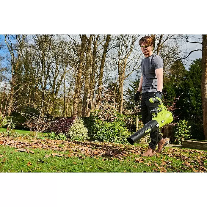 Ryobi Max Power Akku-Laubbläser RY36BLXA-0 - 36 V, Ohne Akku, Blasgeschwindigkeit: 176 km/h, Blasleistung: 15,6 m³/min - Ein Mann benutzt einen lindgrünen und schwarzen Laubbläser, um braune Blätter von einem grünen Rasen zu entfernen.
