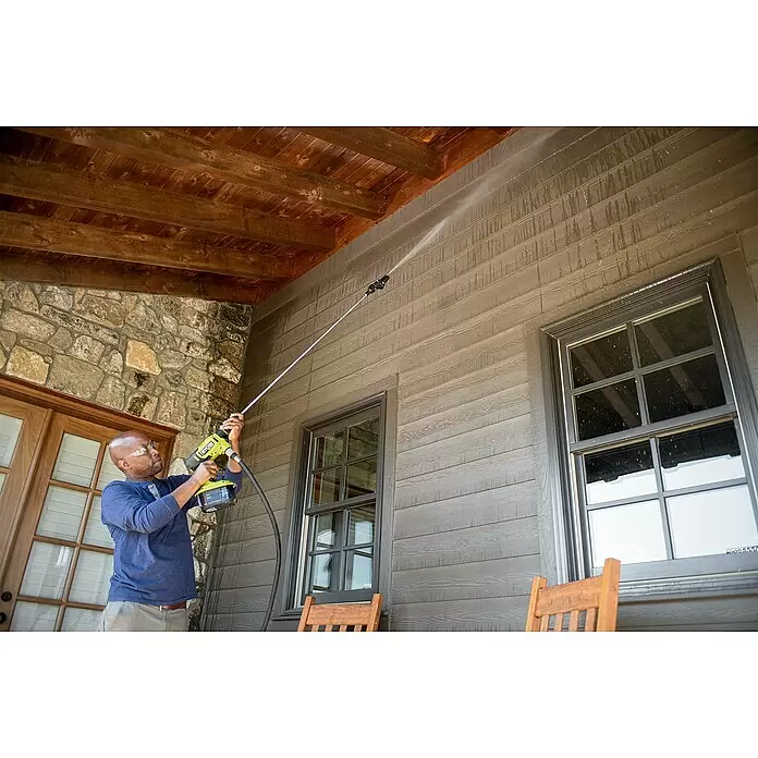 Ryobi Stielverlängerung RAC768 - 1,2 m, Passend für: RYOBI Akku-Mitteldruckreinigern RY18PW22A und RY18PWX41A - Mann in Schutzbrille reinigt Hausfassade mit einem gelb-schwarzen, kabellosen Ryobi Hochdruckreiniger.