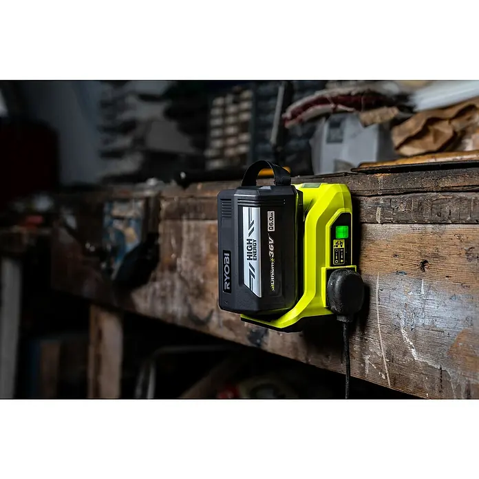 Ryobi Max Power Wechselrichter RY36BI300A-0 - 36 V, Ohne Akku, 300 W - Nahaufnahme eines RYOBI Akku-Ladegeräts mit einem schwarzen Akku, das an einer Werkbank befestigt ist.