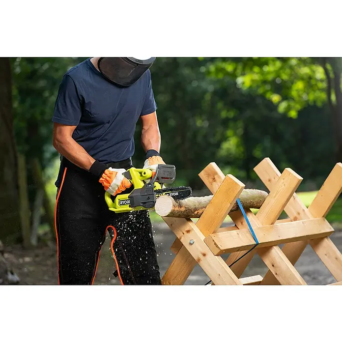 Ryobi ONE+ Akku-Kettensäge RY18CS20A-0 - 18 V, Li-Ionen, Ohne Akku, Schwertlänge: 20 cm - Eine Person sägt Holz mit einer Ryobi Akku-Kettensäge, die grüne Akzente aufweist. Schutzkleidung wird getragen.