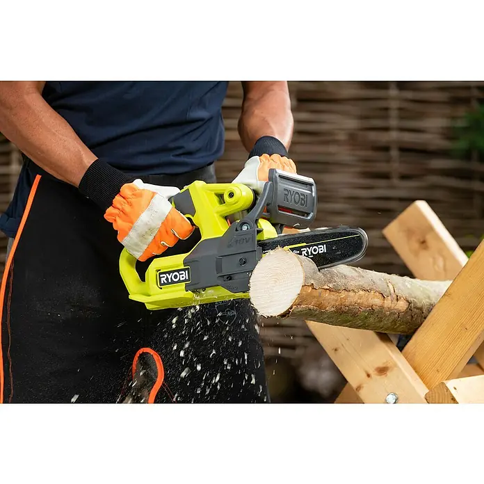 Ryobi ONE+ Akku-Kettensäge RY18CS20A-0 - 18 V, Li-Ionen, Ohne Akku, Schwertlänge: 20 cm - Nahaufnahme einer RYOBI Akku-Kettensäge beim Schneiden eines Baumstamms, bedient von einer Person mit Schutzhandschuhen und -kleidung.