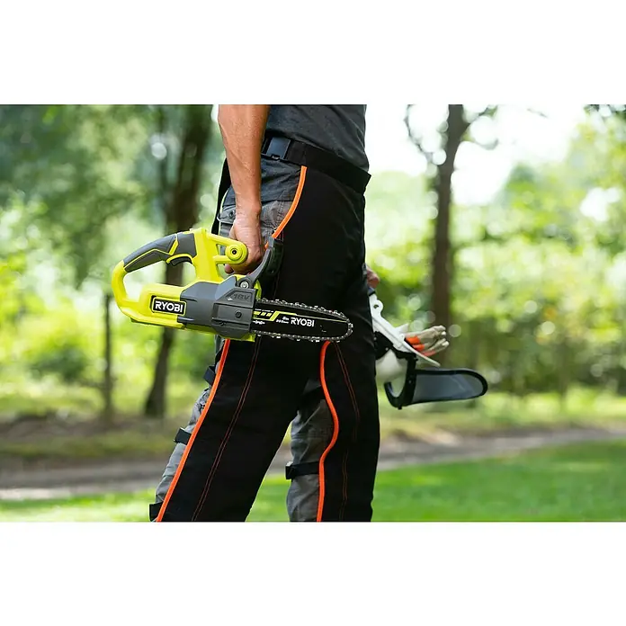 Ryobi ONE+ Akku-Kettensäge RY18CS20A-0 - 18 V, Li-Ionen, Ohne Akku, Schwertlänge: 20 cm - Eine RYOBI Akku-Kettensäge wird von einer Person im Freien gehalten, die Schutzkleidung trägt.