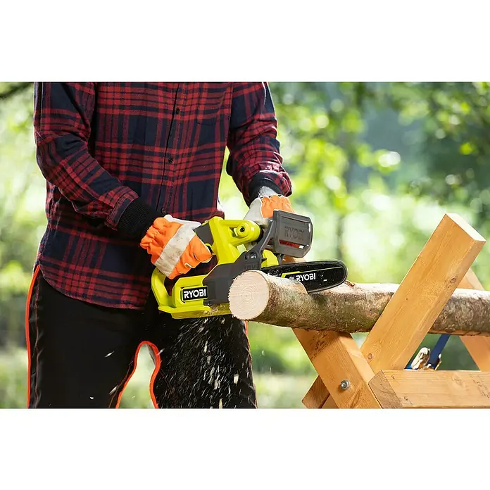 Ryobi ONE+ Akku-Kettensäge RY18CS20A-0 - 18 V, Li-Ionen, Ohne Akku, Schwertlänge: 20 cm - Ein Mann in Arbeitskleidung benutzt eine RYOBI Akku-Kettensäge, um einen Baumstamm auf einem Holzbock im Freien zu sägen.