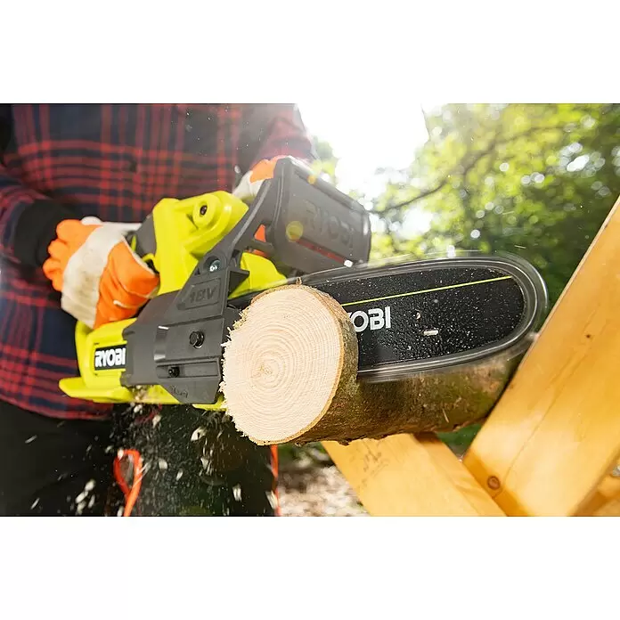 Ryobi ONE+ Akku-Kettensäge RY18CS20A-0 - 18 V, Li-Ionen, Ohne Akku, Schwertlänge: 20 cm - Eine Person nutzt eine gelb-schwarze Ryobi Kettensäge, um einen Holzstamm zu zersägen, wobei Holzspäne fliegen.