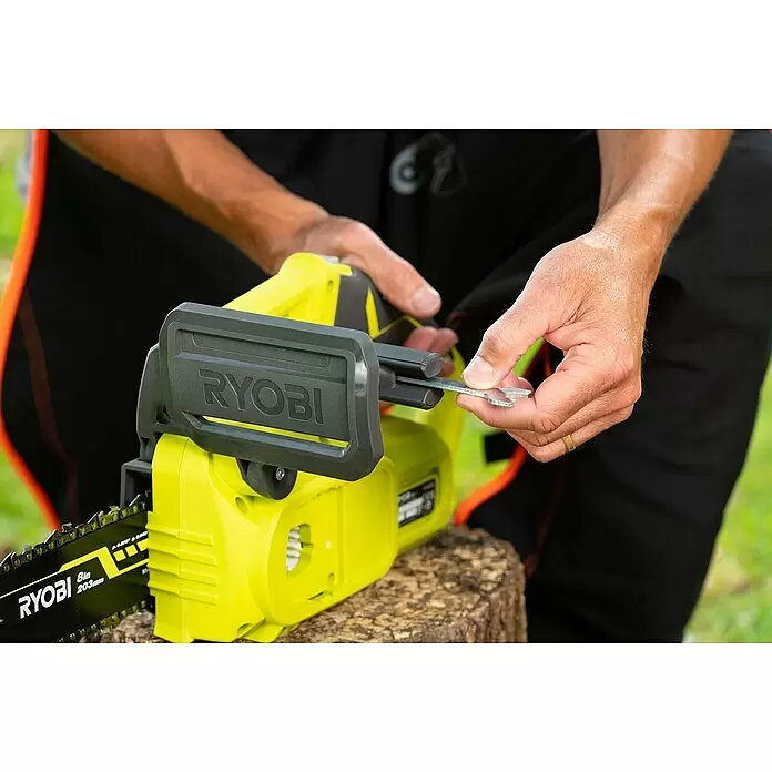 Ryobi ONE+ Akku-Kettensäge RY18CS20A-0 - 18 V, Li-Ionen, Ohne Akku, Schwertlänge: 20 cm - Hände justieren eine grüne und schwarze Ryobi Kettensäge mit einem kleinen Schraubenschlüssel auf einem Baumstamm.