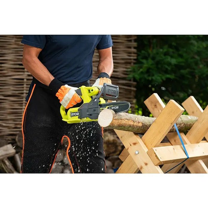 Ryobi ONE+ Akku-Kettensäge RY18CS20A-0 - 18 V, Li-Ionen, Ohne Akku, Schwertlänge: 20 cm - Nahaufnahme einer Person, die mit einer gelben Ryobi Akku-Kettensäge ein Holzstück auf einem Holzbock zersägt.