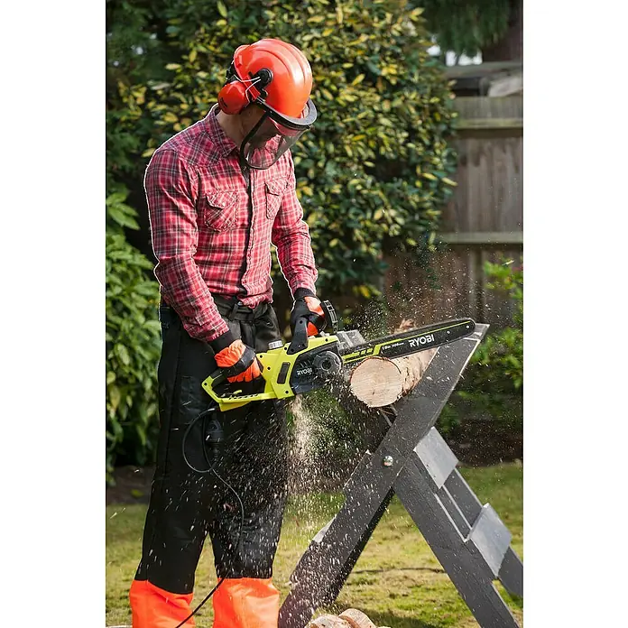 Ryobi Motosierra eléctrica RCS2340B - 2.300 W, Longitud de la cuchilla: 40 cm - Un hombre en el jardín corta madera con una motosierra Ryobi amarilla mientras usa ropa protectora.
