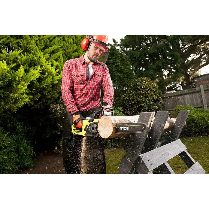 Ryobi Elektro-Kettensäge RCS2340B - 2.300 W, Schwertlänge: 40 cm - Ein Mann benutzt eine Ryobi Kettensäge, um Holz im Garten zu schneiden, mit Sicherheitsausrüstung für sicheres Arbeiten.