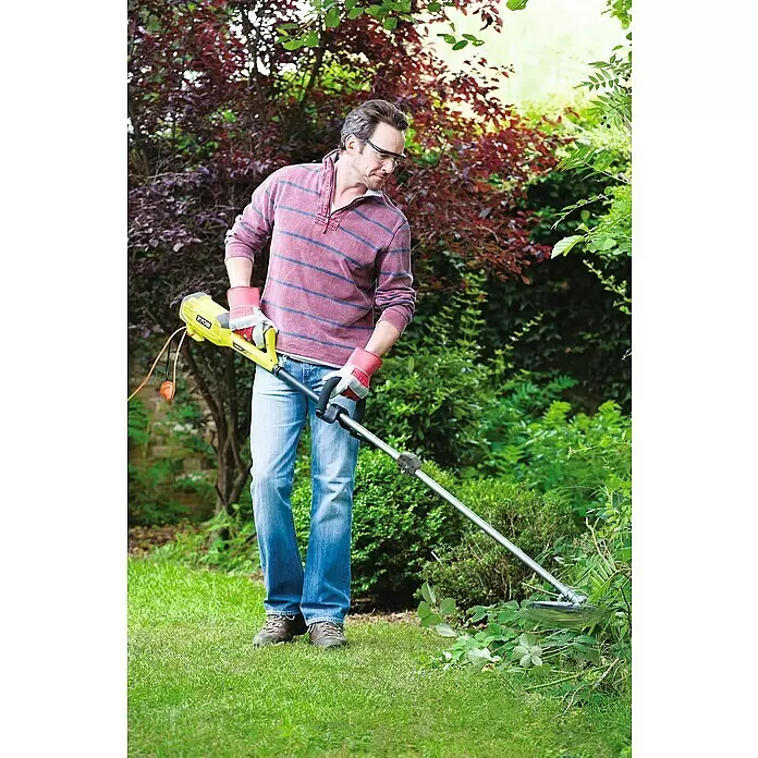 Ryobi Elektro-Motorsense RBC1226I - 1.200 W, Schnittbreite Faden: 38 cm, Schnittbreite Messer: 26 cm - Ein Mann im Garten schneidet Unkraut mit einem gelb-schwarzen Ryobi Rasentrimmer, trägt Schutzbrille und Handschuhe.
