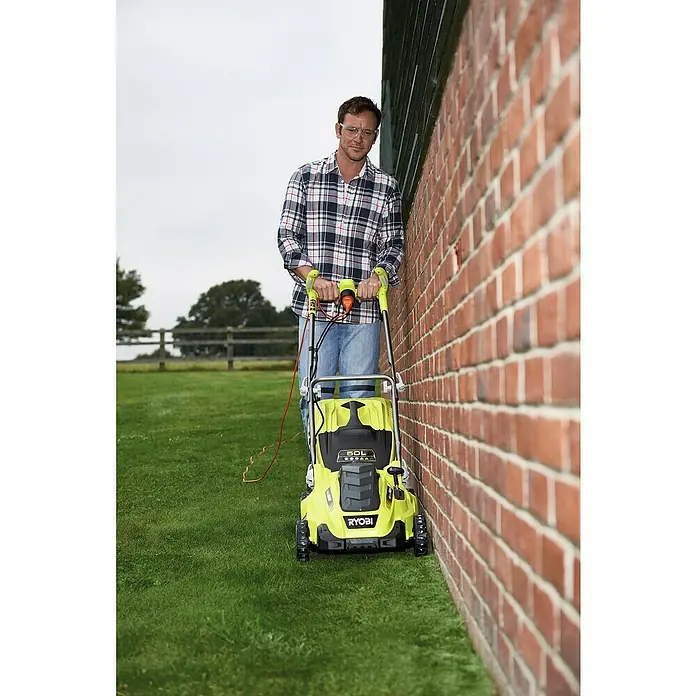 Ryobi Elektro-Rasenmäher RLM18E40H - 1.800 W, Schnittbreite: 40 cm - Mann, der Rasen mit einem gelben Ryobi-Elektro-Rasenmäher mit Kabel mäht, während er eine Schutzbrille und ein kariertes Hemd trägt.