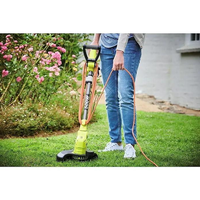 Ryobi Elektro-Rasentrimmer RLT5127 - 500 W, Schnittbreite Faden: 27 cm - Person hält einen Rasentrimmer mit einem 500W-Motor in einem Garten mit Blumen.