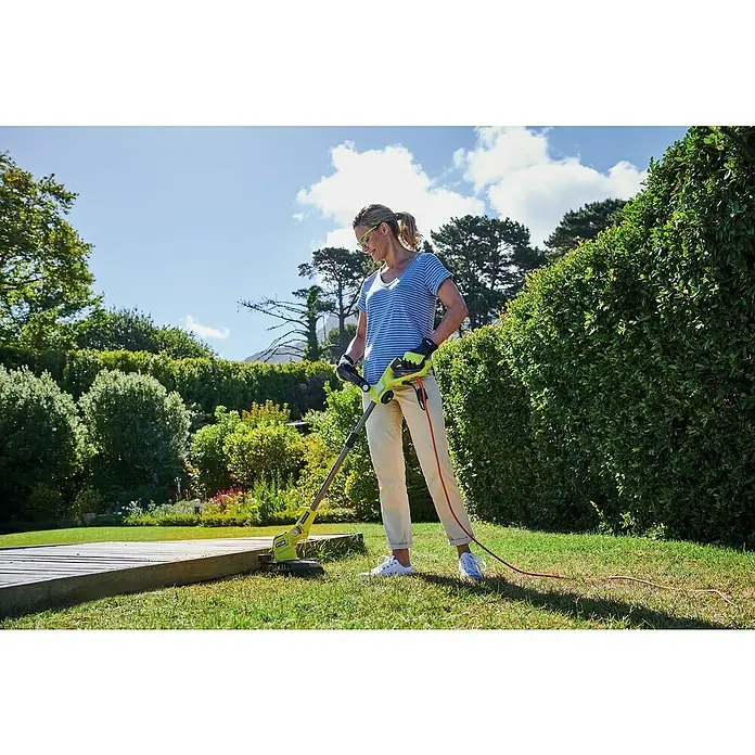 Ryobi Elektro-Rasentrimmer RLT6130 - 600 W, Schnittbreite Faden: 30 cm - Frau trimmt den Rasen mit einem RYOBI Rasentrimmer mit Akku. Praktisches und einfaches Gartengerät für den Außenbereich.