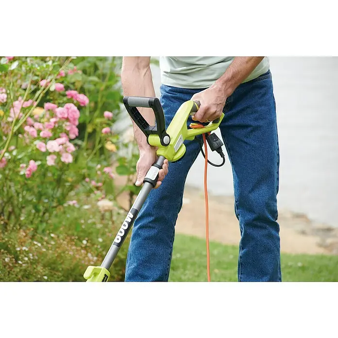 Ryobi Elektro-Rasentrimmer RLT6130 - 600 W, Schnittbreite Faden: 30 cm - Nahaufnahme einer Person, die einen Sun Joe Trimmer/Edger in einem Garten mit blühenden Rosen bedient.
