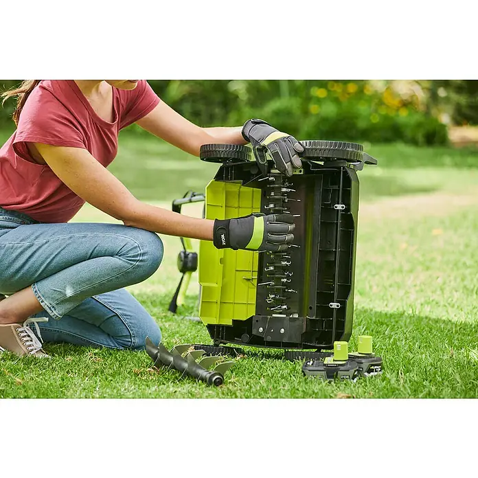 Ryobi ONE+ Akku-Vertikutierer RY18SFX35A-0 - Anzahl Akkus: Ohne Akku, 18 V, Arbeitsbreite: 35 cm - Frau inspiziert einen Ryobi Rasenlüfter mit Vertikutierwalze und zwei Akkus auf einer grünen Wiese.