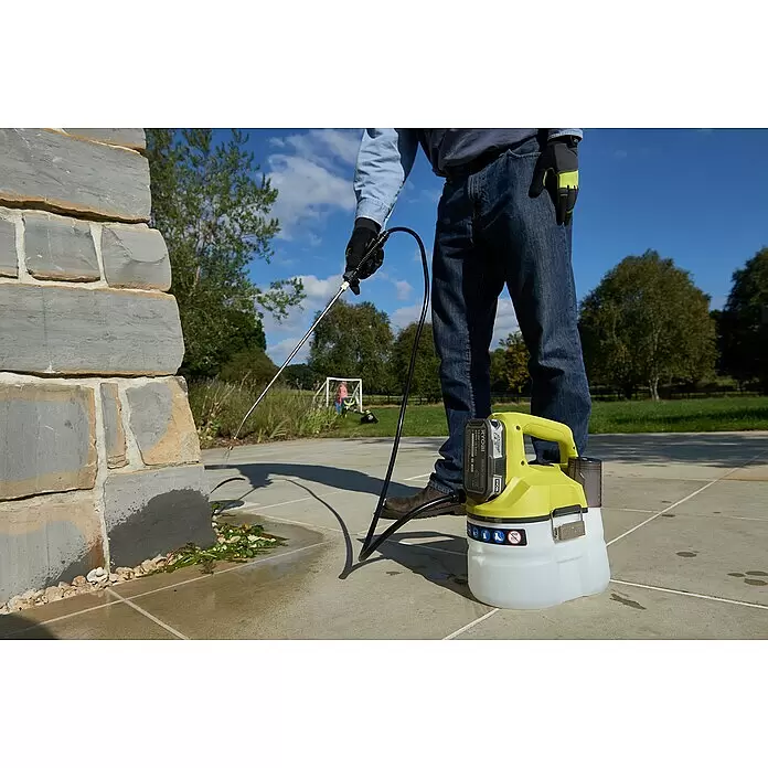 Ryobi ONE+ Akku-Sprühgerät OWS1880 - 18 V, Anzahl Akkus: Ohne Akku, 3,5 l - Eine Person besprüht eine Steinmauer mit einem gelb-weißen Ryobi 18V 2.5Ah Sprühgerät. Das Akku-Sprühgerät steht auf dem Boden.