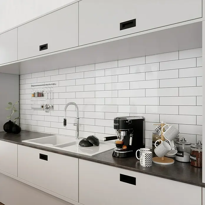 Modern Style Wandfliese Alboran Blanco - 7,5 x 30 cm, Weiß, Glänzend - Elegante Küche mit weißen Schränken, dunkler Arbeitsplatte und einer schwarzen Espressomaschine, die eine warme Atmosphäre erzeugt.