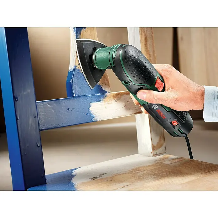 Bosch Elektro-Multifunktionswerkzeug PMF 220 CE - 220 W, STARLOCK-System - Nahaufnahme eines Bosch Multifunktionswerkzeugs beim Abschleifen eines Holzstuhls.
