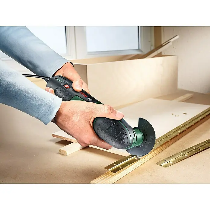 Bosch Elektro-Multifunktionswerkzeug PMF 220 CE - 220 W, STARLOCK-System - Nahaufnahme eines Bosch-Multifunktionswerkzeugs beim Schneiden von Holz, ideal für Heimwerkerarbeiten und präzise Schnitte.